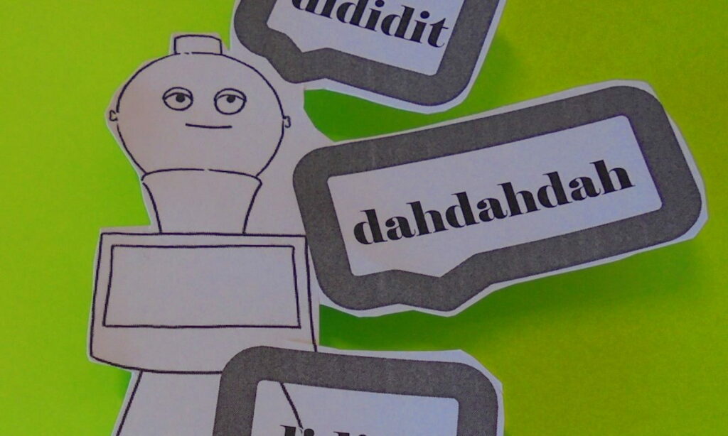 Ein Roboter aus Papier mit dem Schriftzug "dahahahah" auf grünem Grund